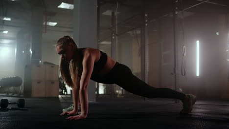 A-woman-does-stretching-exercises-in-a-dark-fitness-room-after-a-workout-Fitness-woman-working-out-on-core-muscles-at-dark-gym